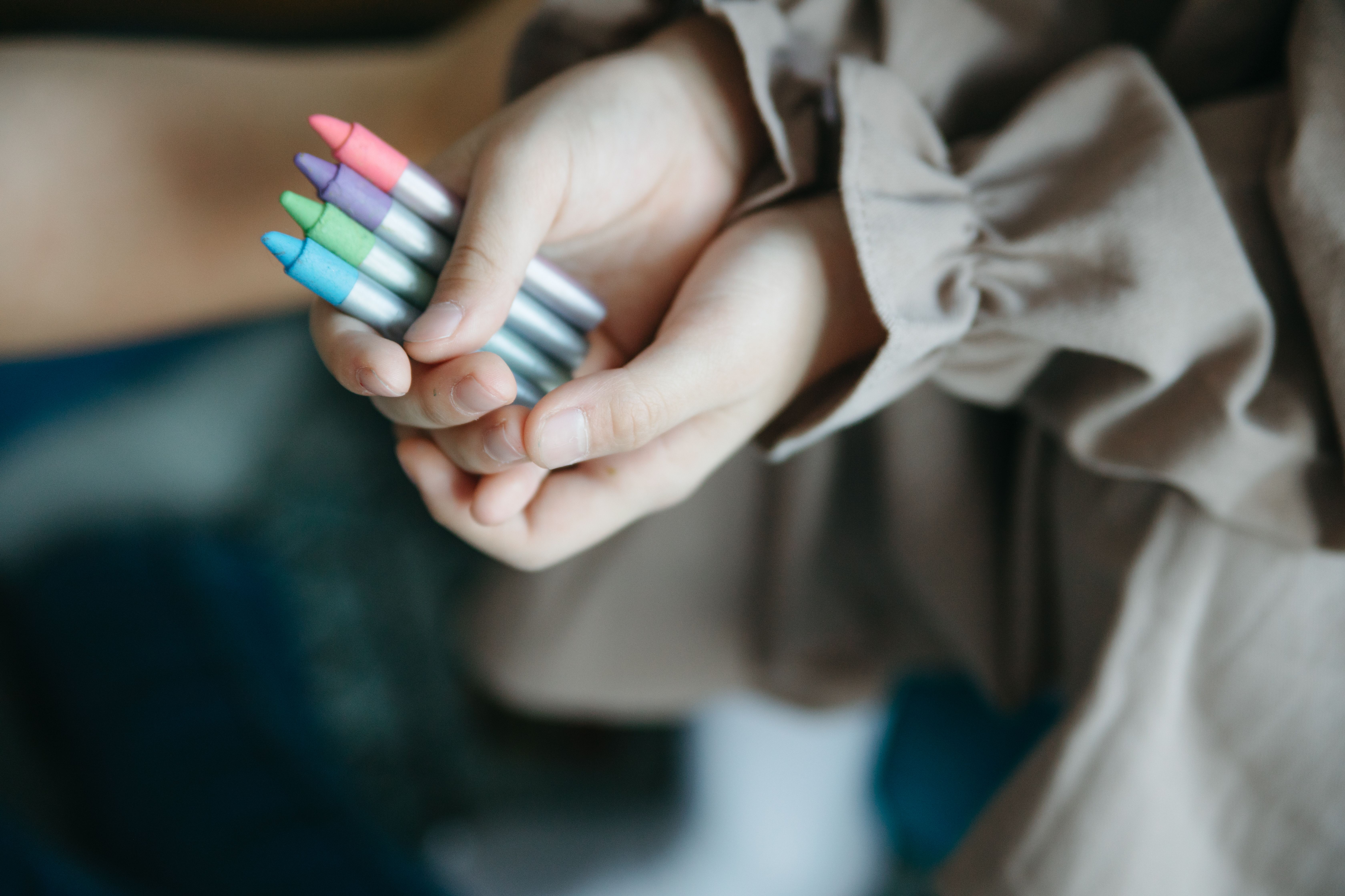 クレヨンを手に取る子どもの手のイメージ
